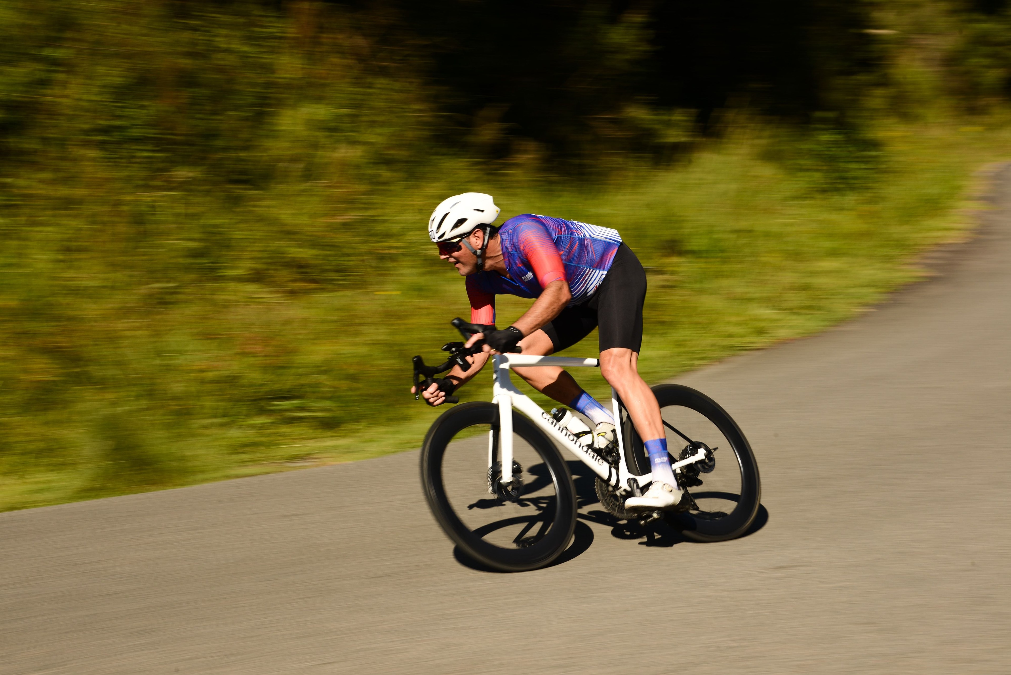 Road cyclist carrying speed through a sunlit corner
